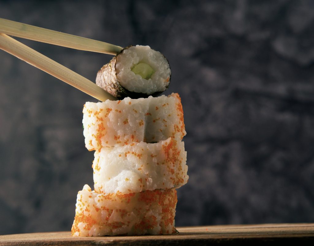 Close-up of a delicious sushi stack with chopsticks, showcasing Japanese culinary art.