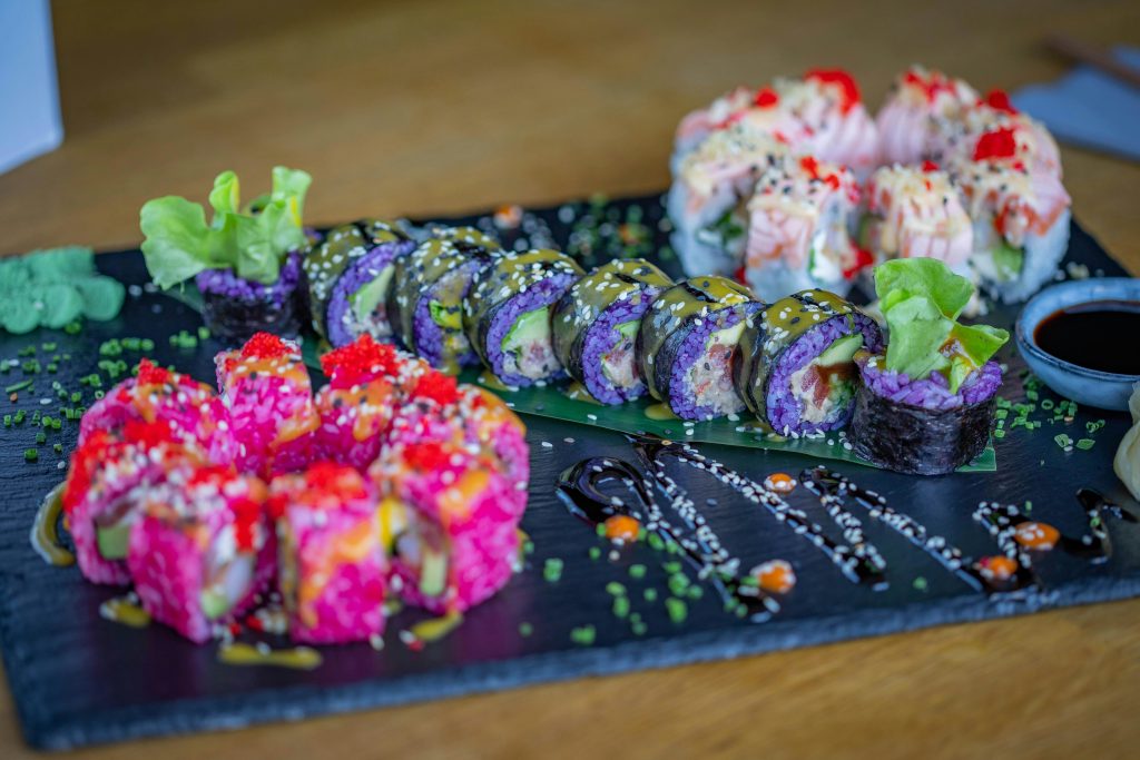 Colorful sushi platter with diverse rolls, garnishes, and soy sauce, perfect for food photography.