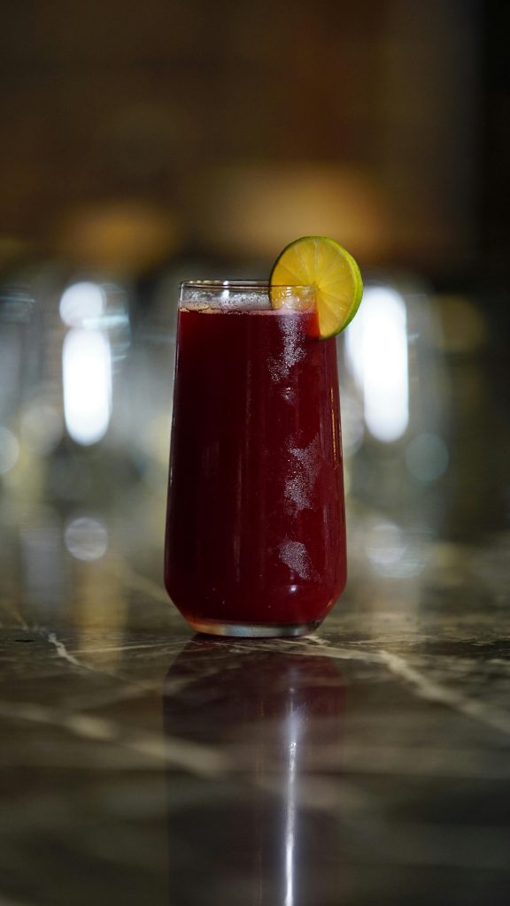 Chilled hibiscus beverage in a glass with a lime slice, perfect for summer refreshment.